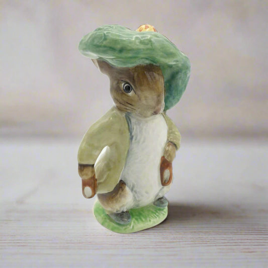 Porcelain figurine of a rabbit wearing a green hat on a wooden surface