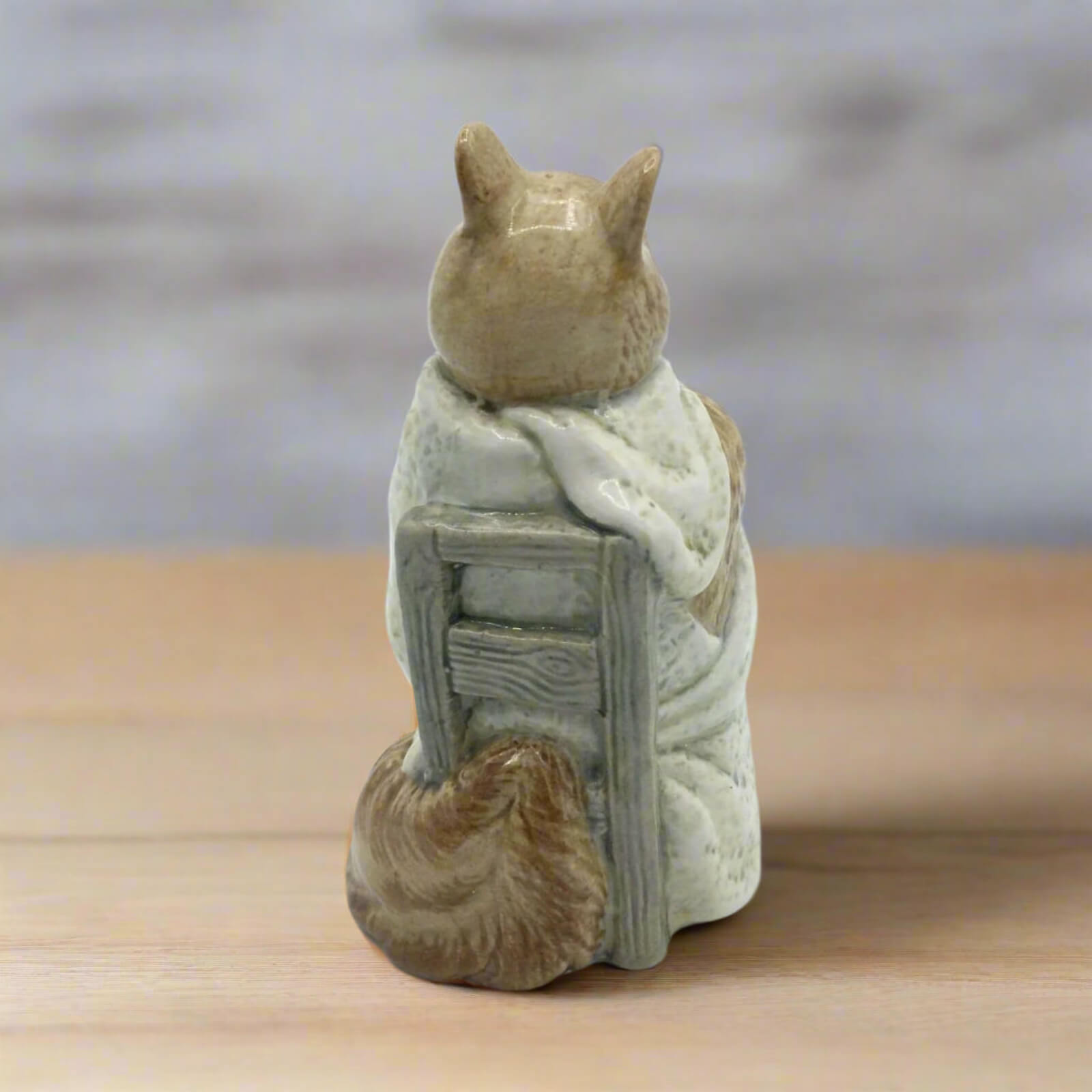 Chippy Hackee figurine wrapped in a blanket on a wooden surface with a blurred background