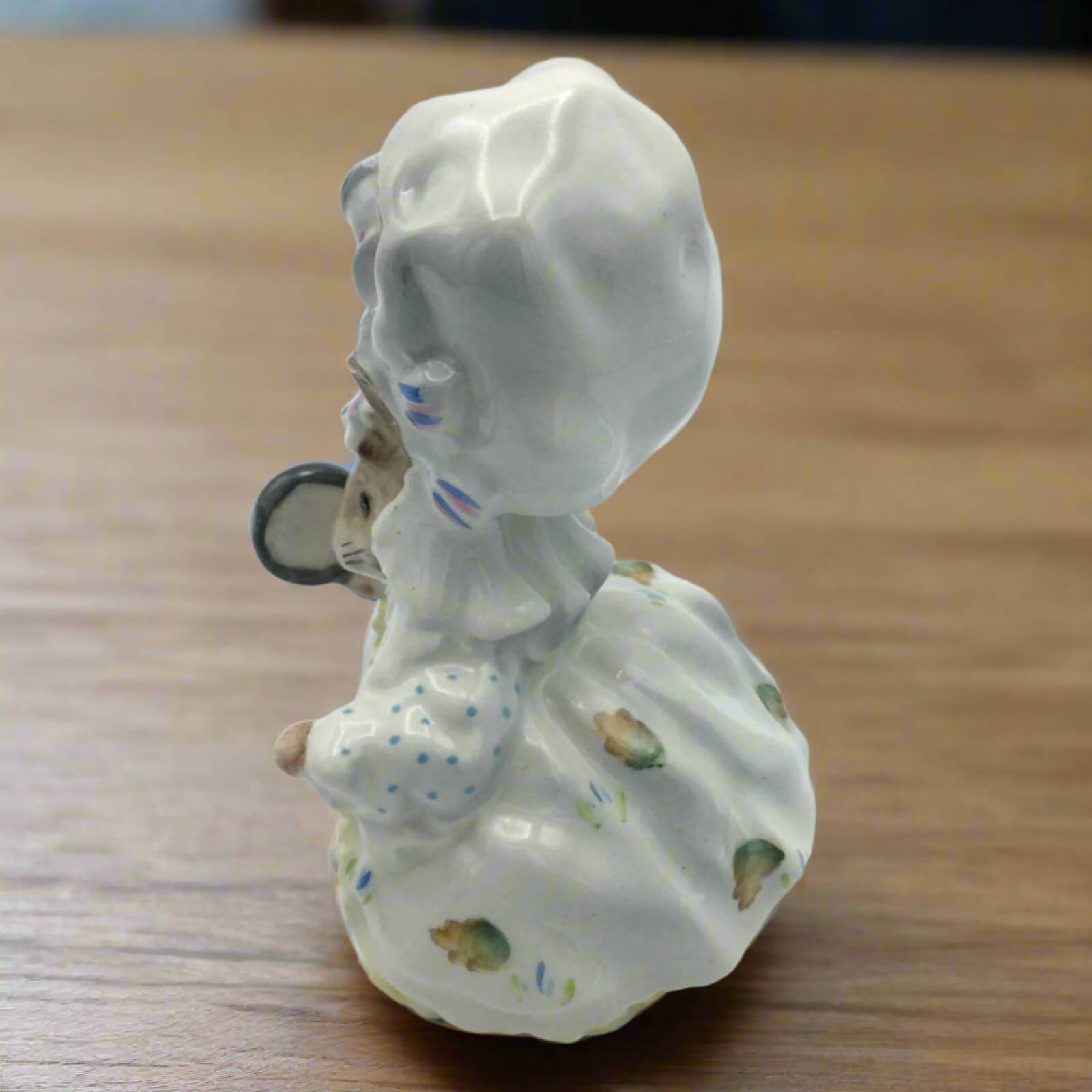 Porcelain figurine of a woman with a child on her back on a wooden surface