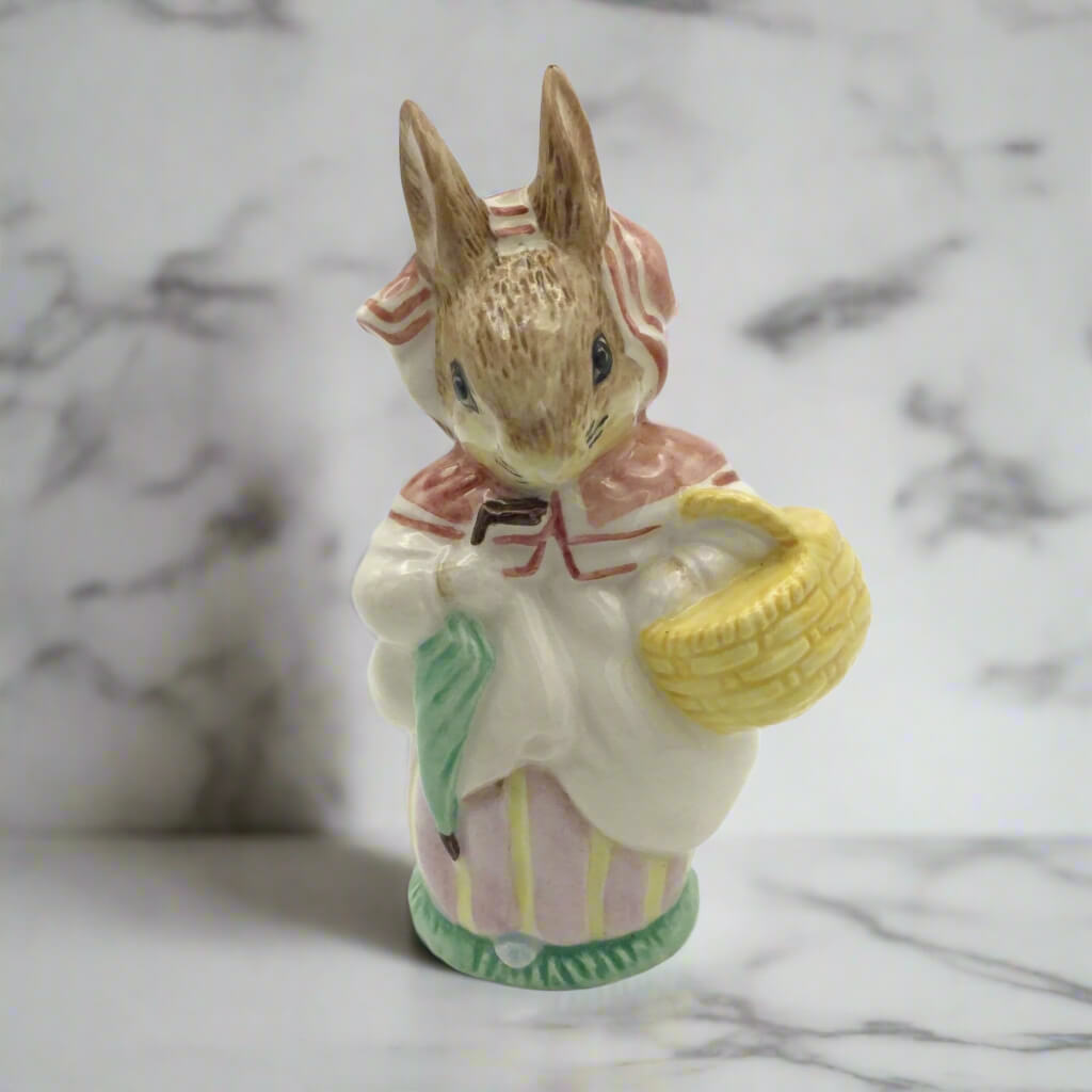 Small ceramic figurine of a rabbit holding a basket on a marble surface