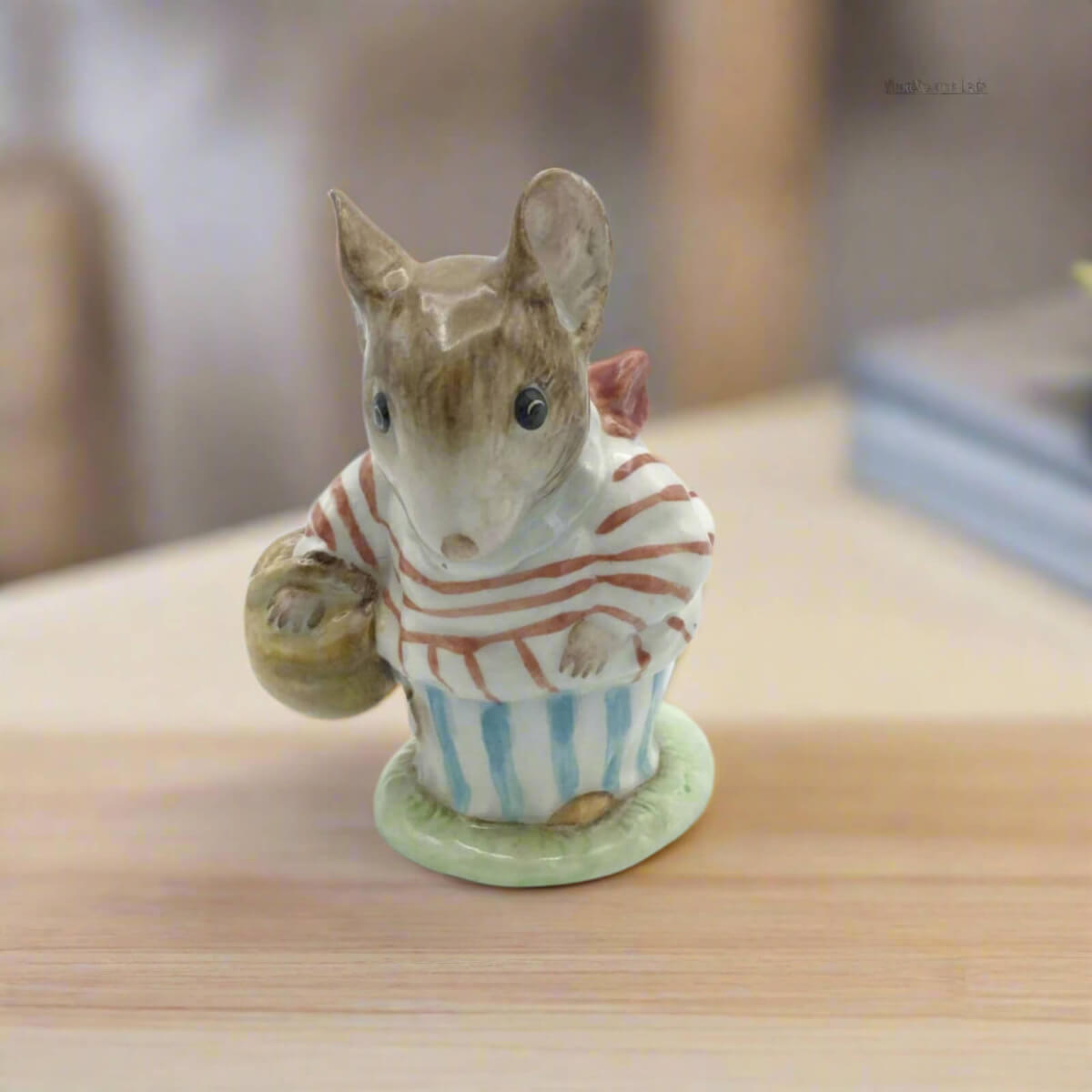 Small ceramic mouse figurine holding a basket on a wooden surface