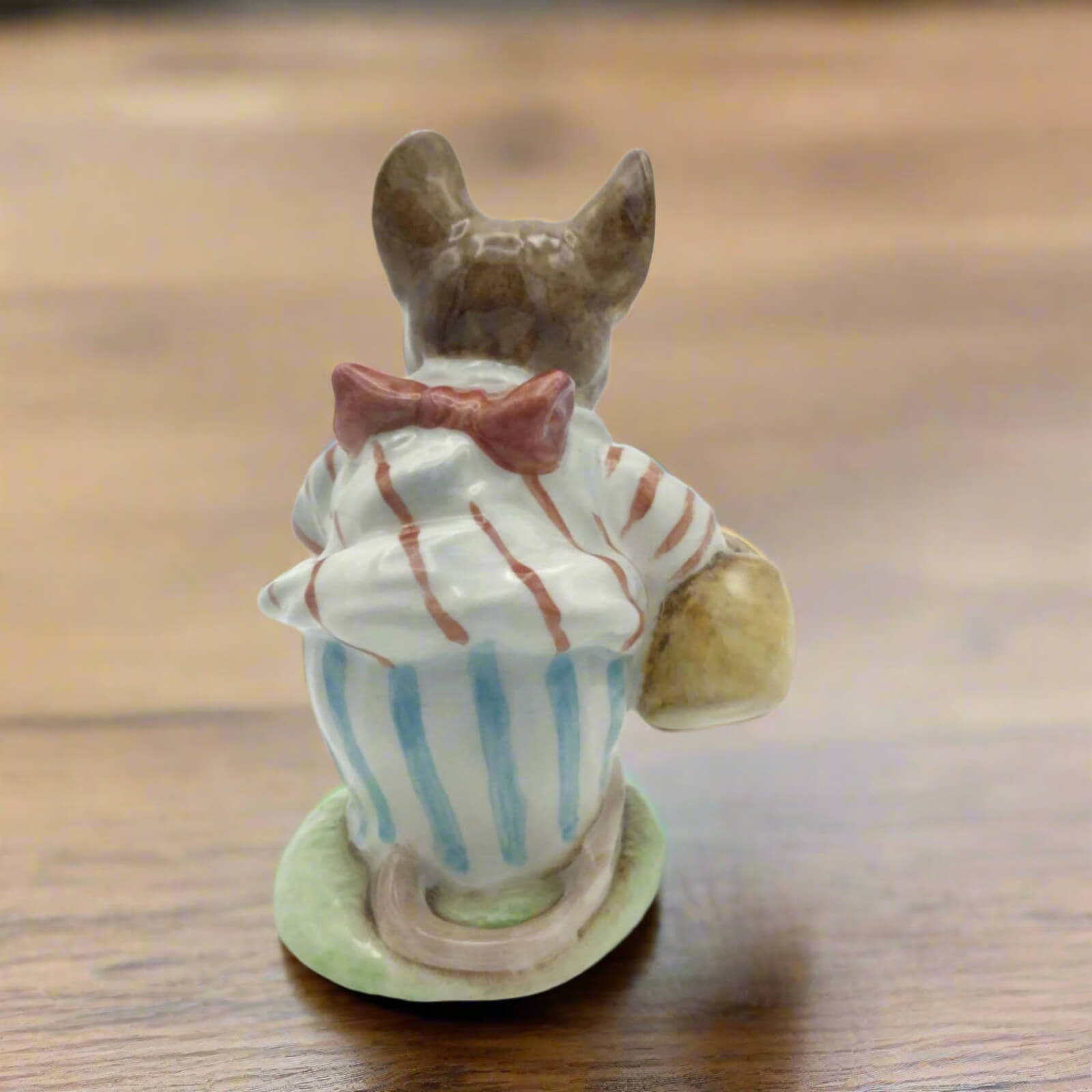 Small ceramic figure of a character with a striped outfit and bow tie on a wooden surface