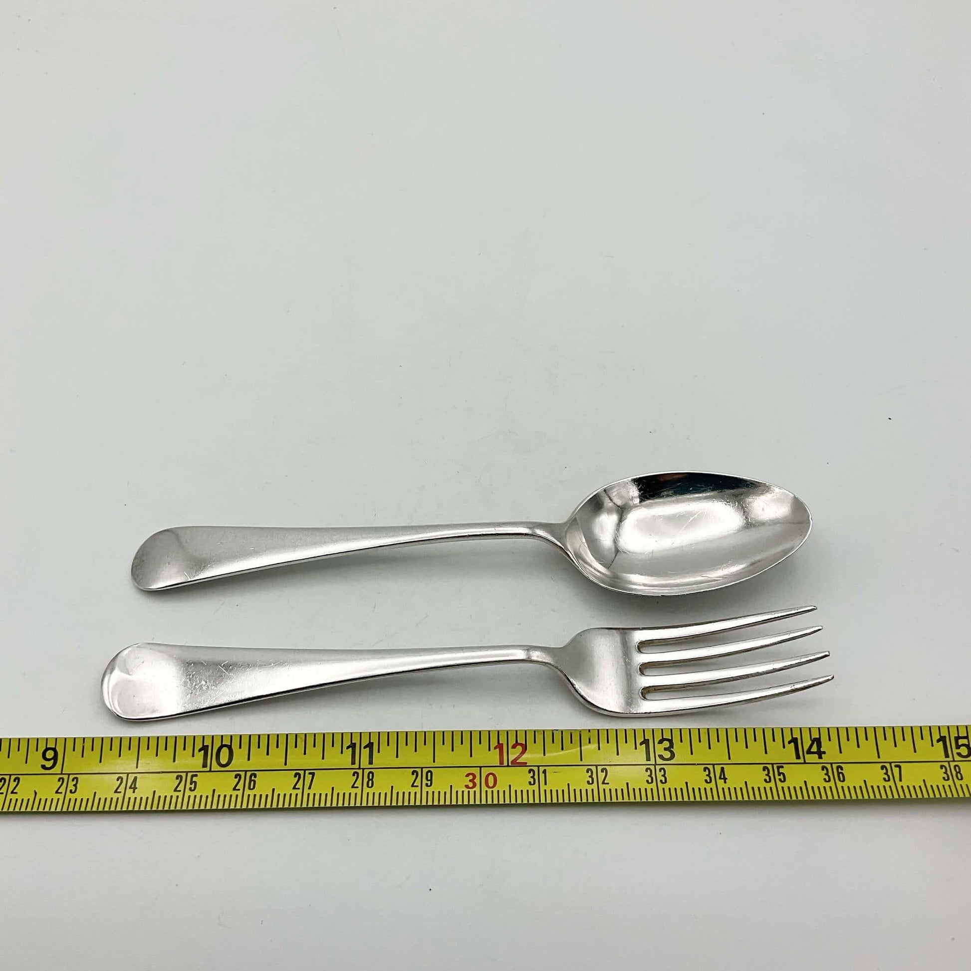 Silver spoon and fork next to tape measure showing they measure approximately 13cm in length