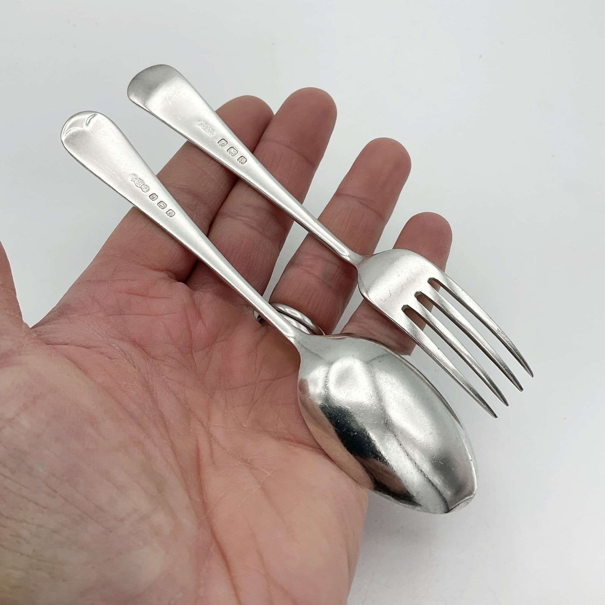 Small spoon and fork set upside down on a hand