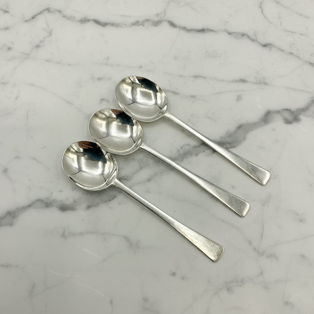 Four silver spoons on a marble surface