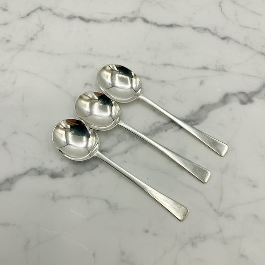 Four silver spoons on a marble surface