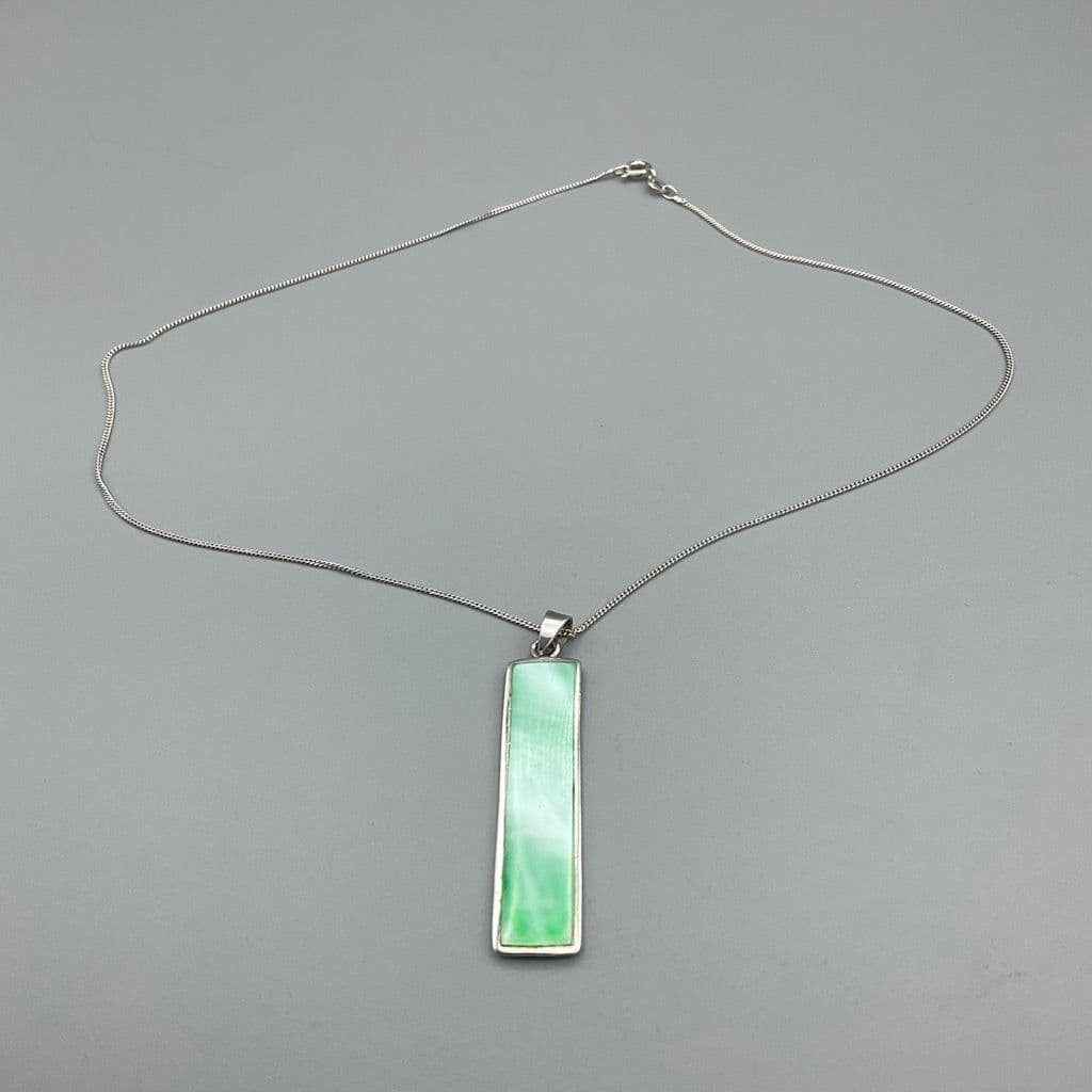Green mother of pearl pendant necklace on a plain background