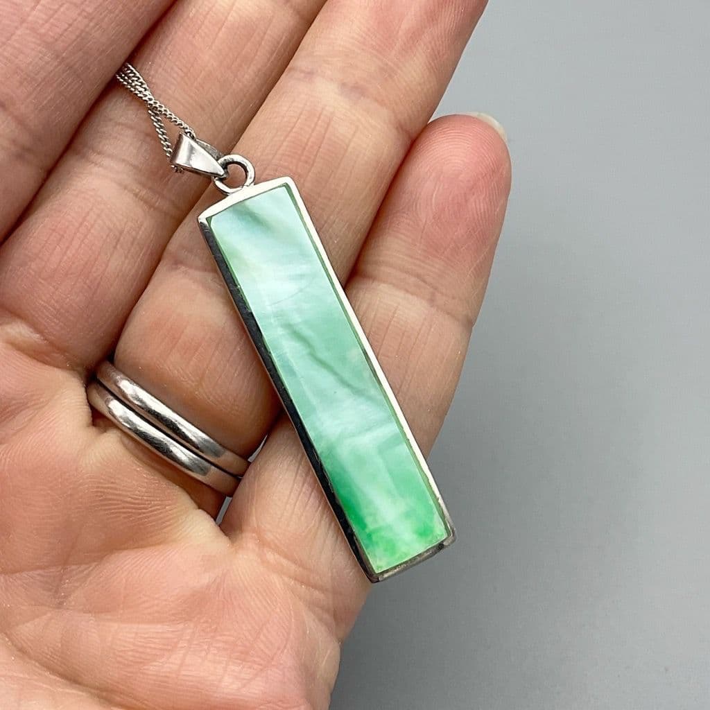 Green mother of pearl pendant necklace held in a hand