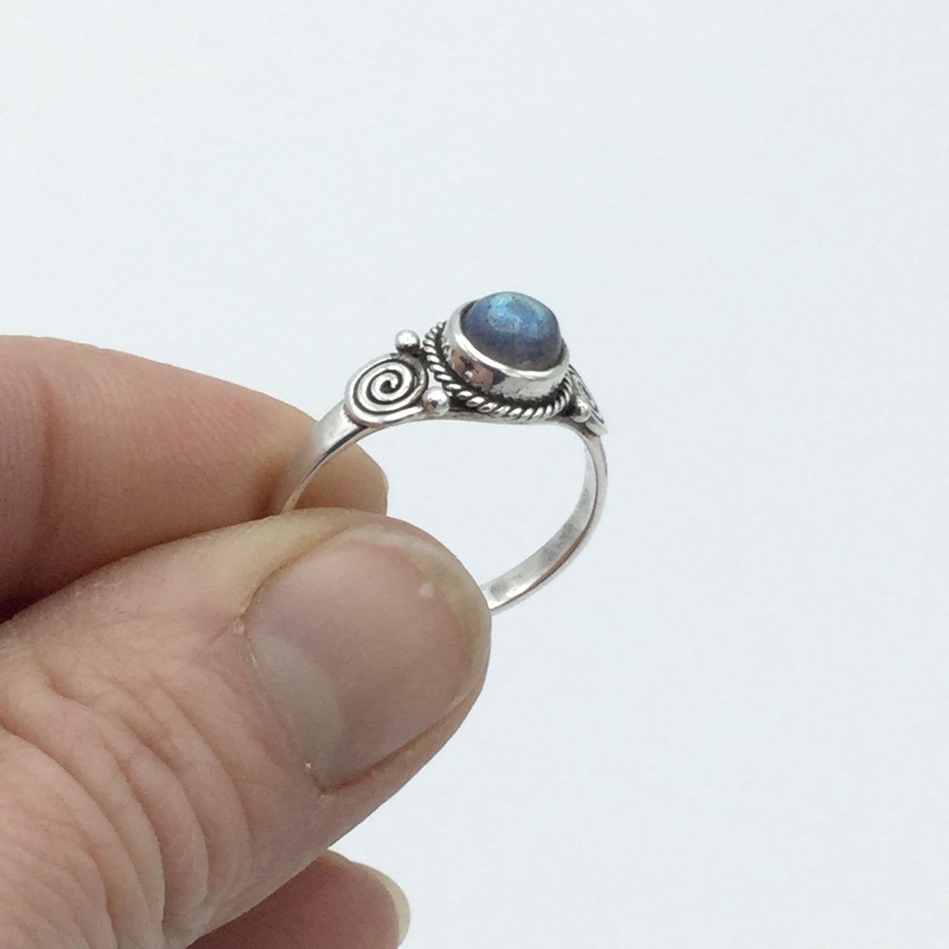 A blue moonstone silver ring held in fingers