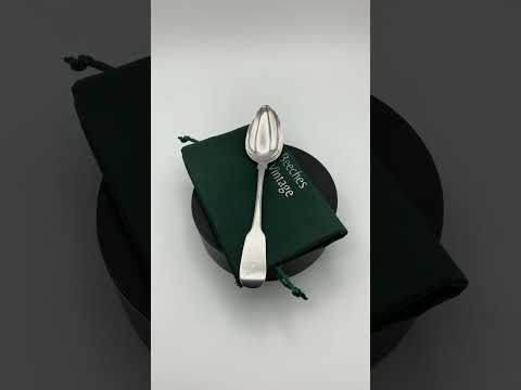 Silver dessert spoon on a green cotton gift bag Video short on a turntable