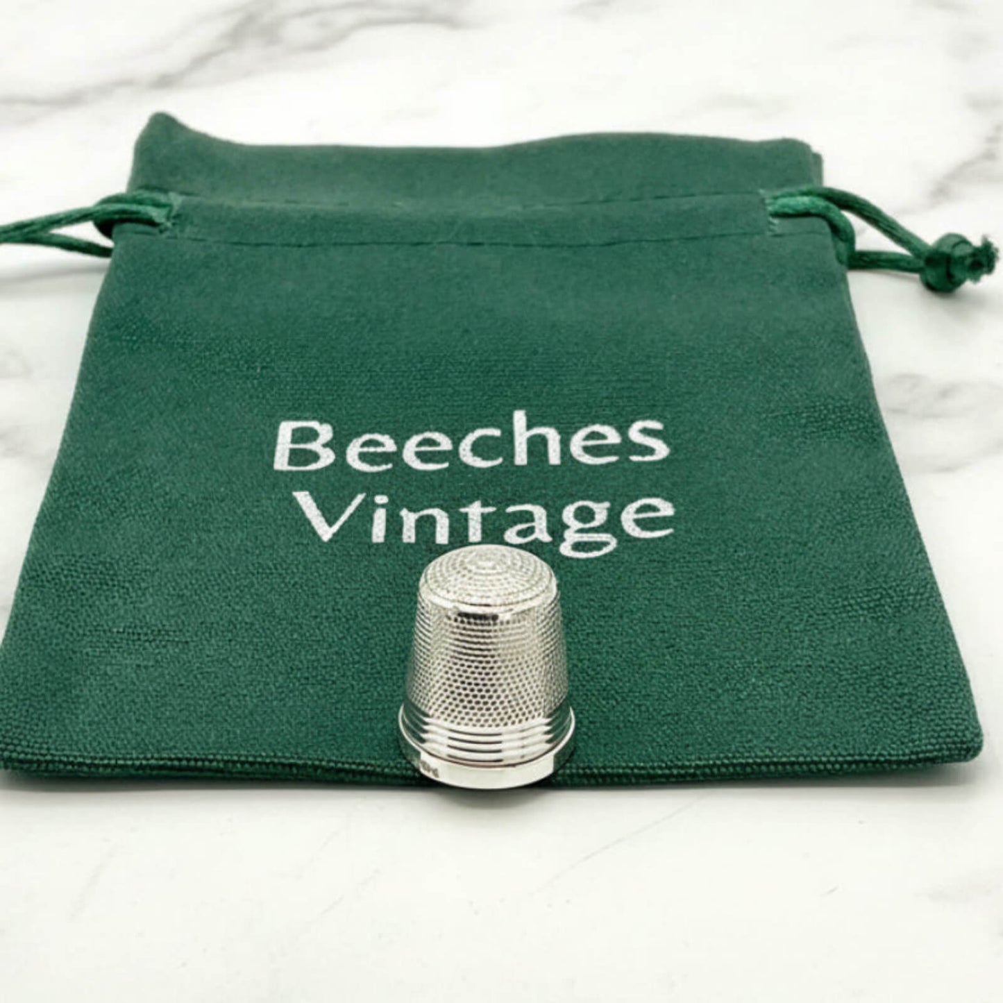 Silver thimble on a green drawstring bag with 'Beeches Vintage' text.