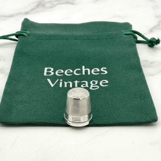 Silver thimble on a green drawstring bag with 'Beeches Vintage' text.