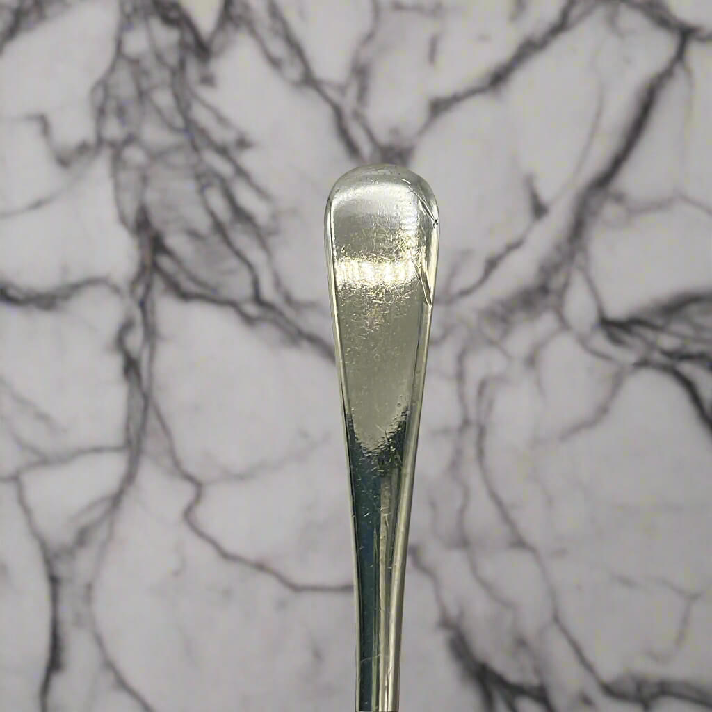 Silver spoon handle on a marble surface