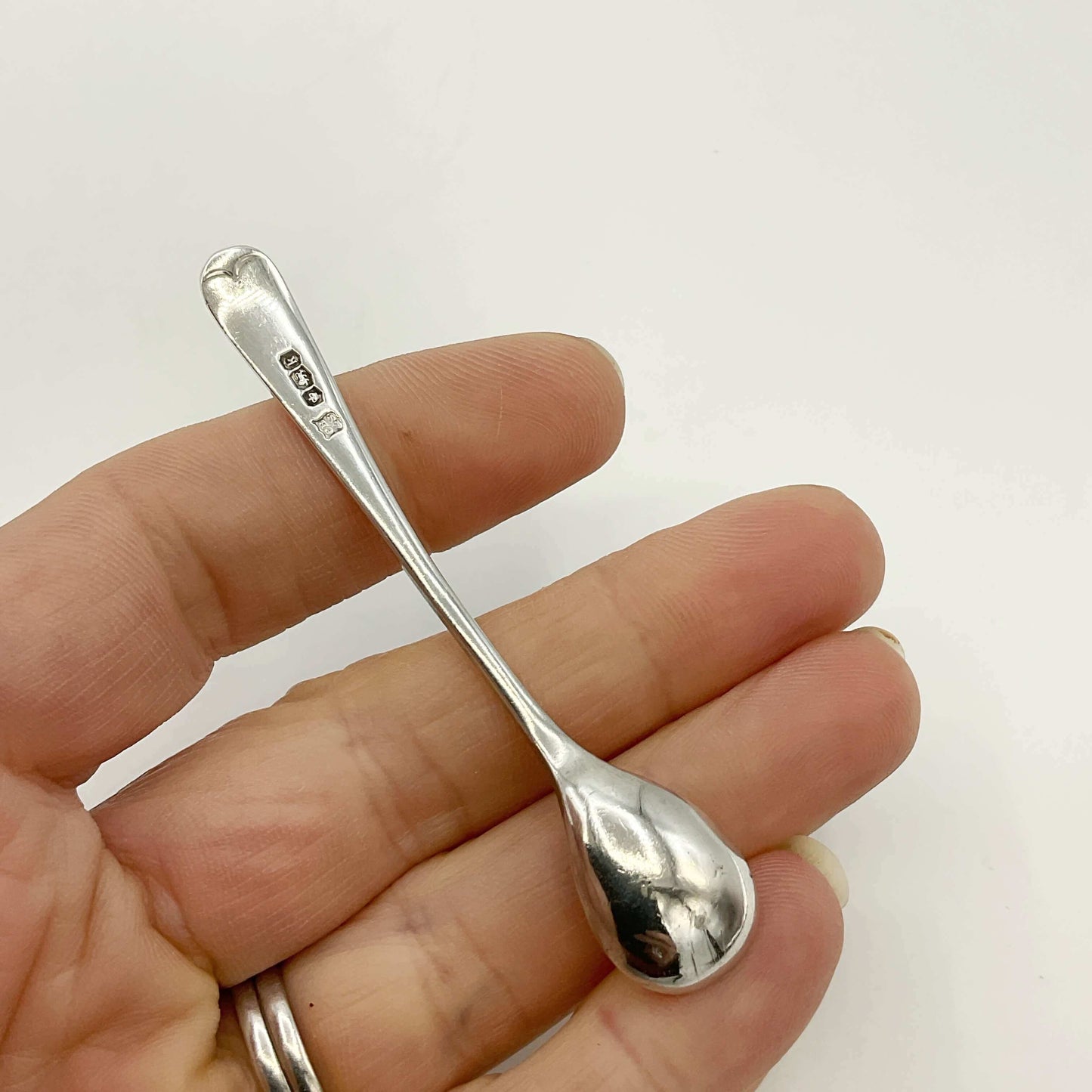 Silver spoon held between fingers against a white background