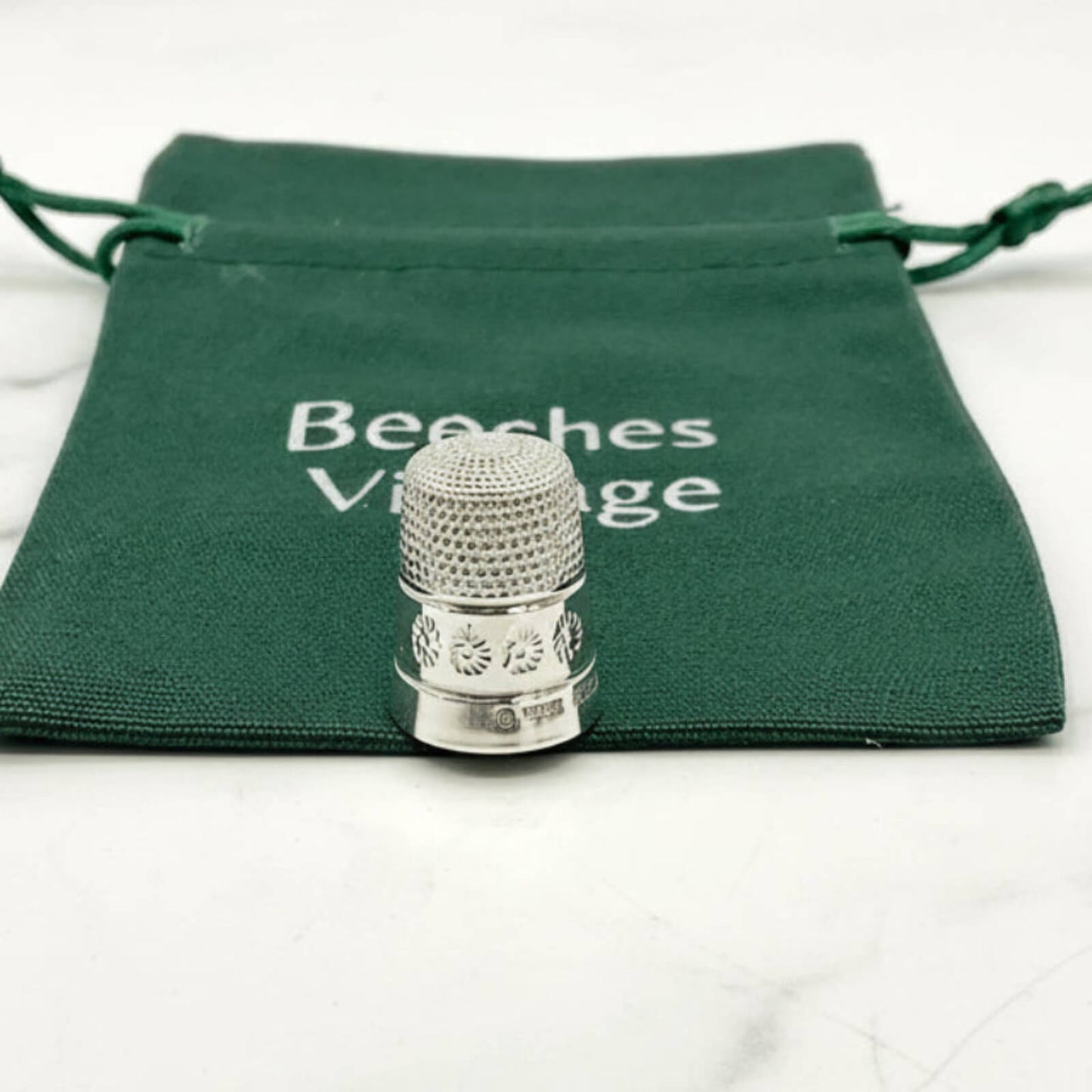 Silver thimble on a green drawstring bag with 'Beeches Vintage' text.