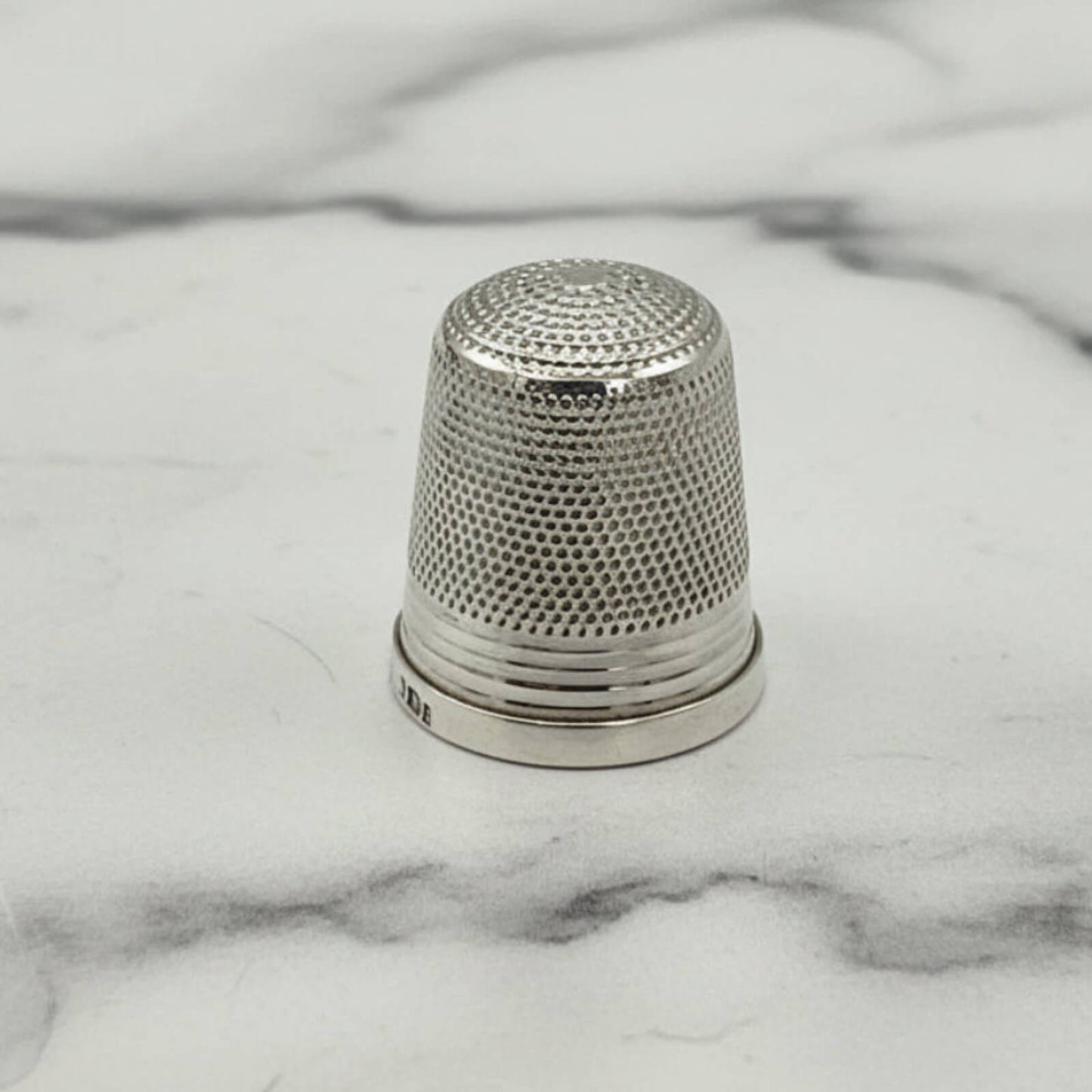 Silver thimble on a marble surface