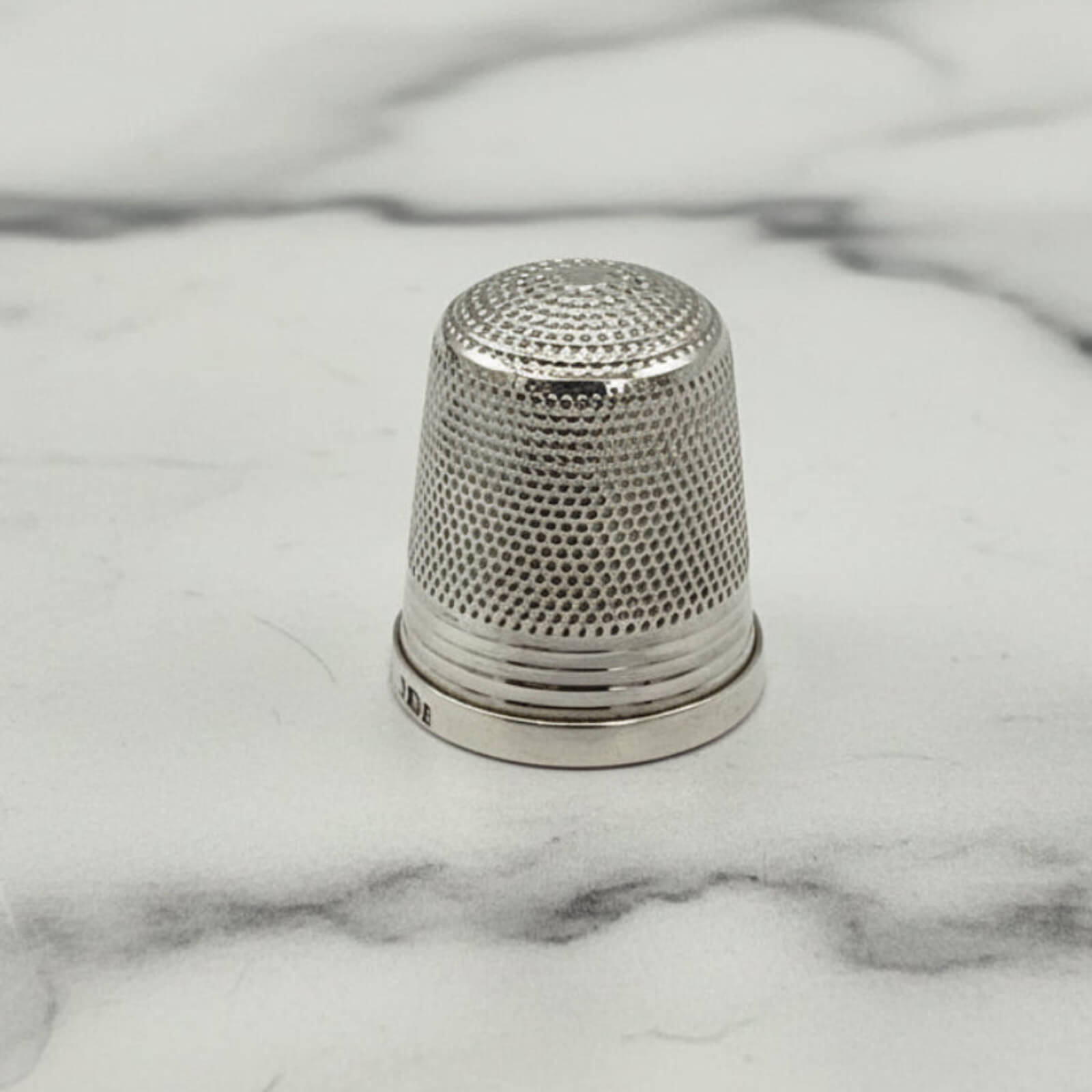 Silver thimble on a marble surface