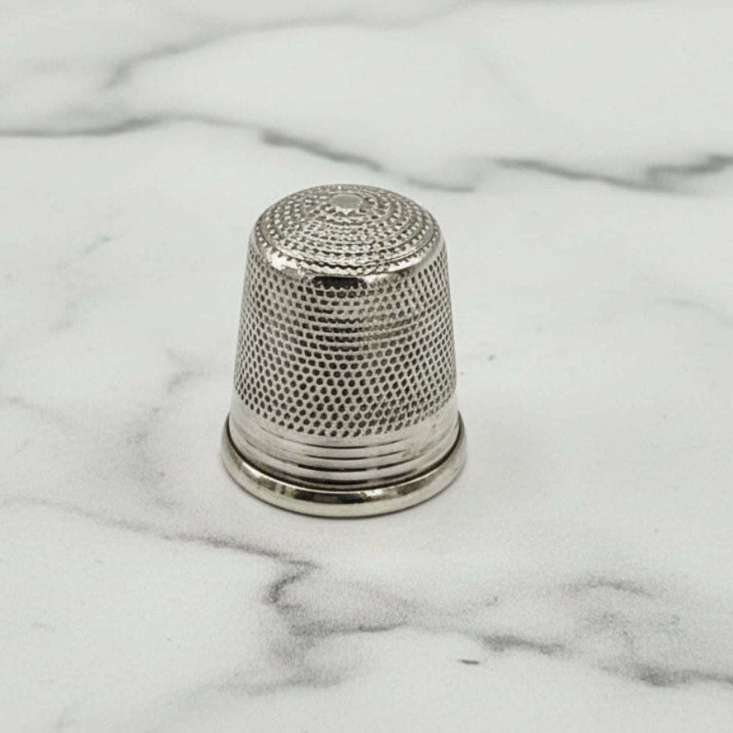 Silver thimble on a marble surface