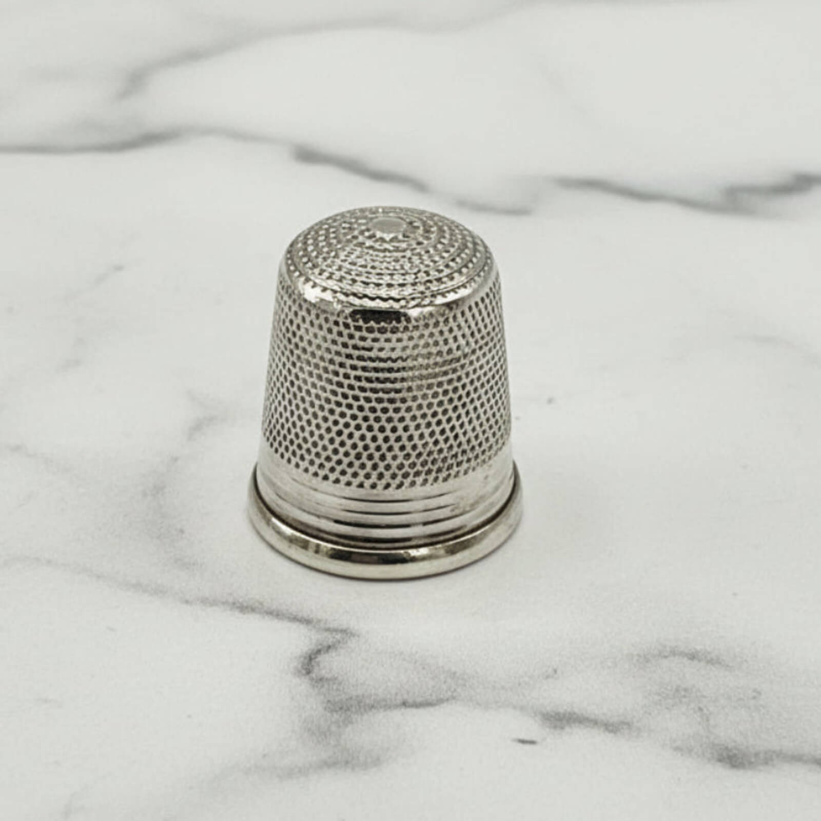 Silver thimble on a marble surface