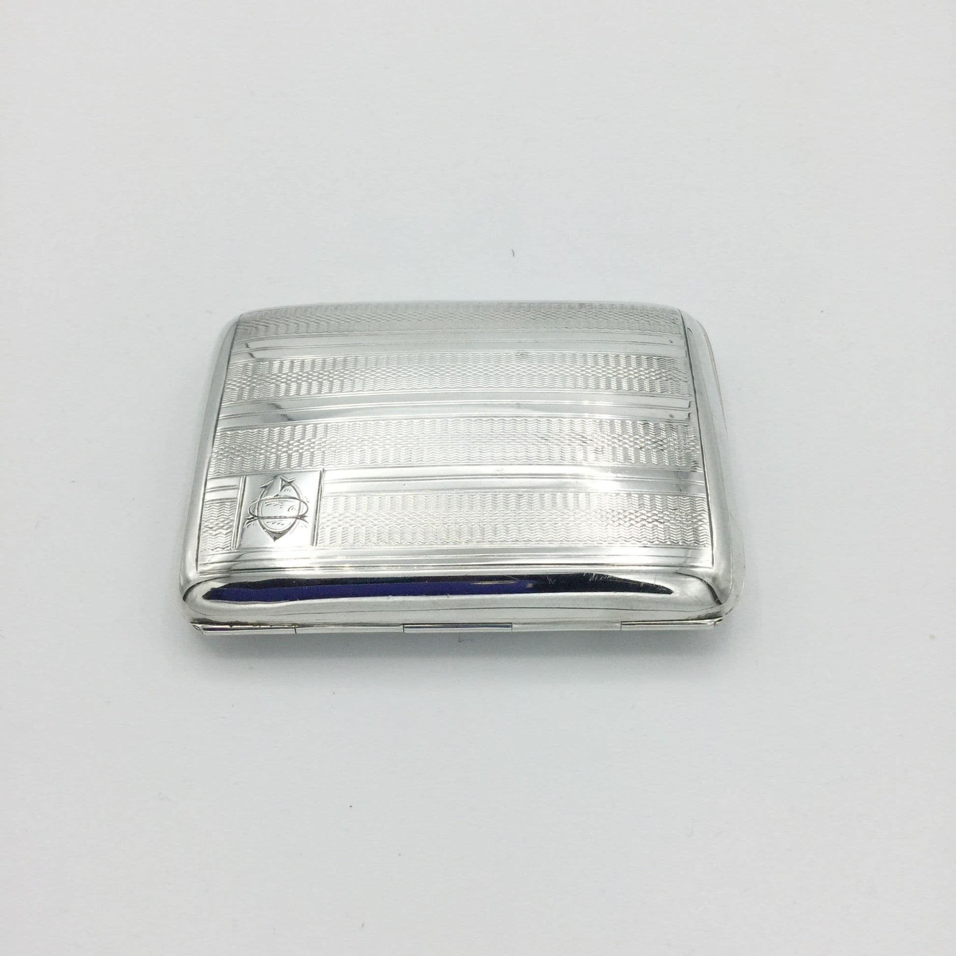 1930s vintage silver cigarette case viewed from the hinge side on a white background