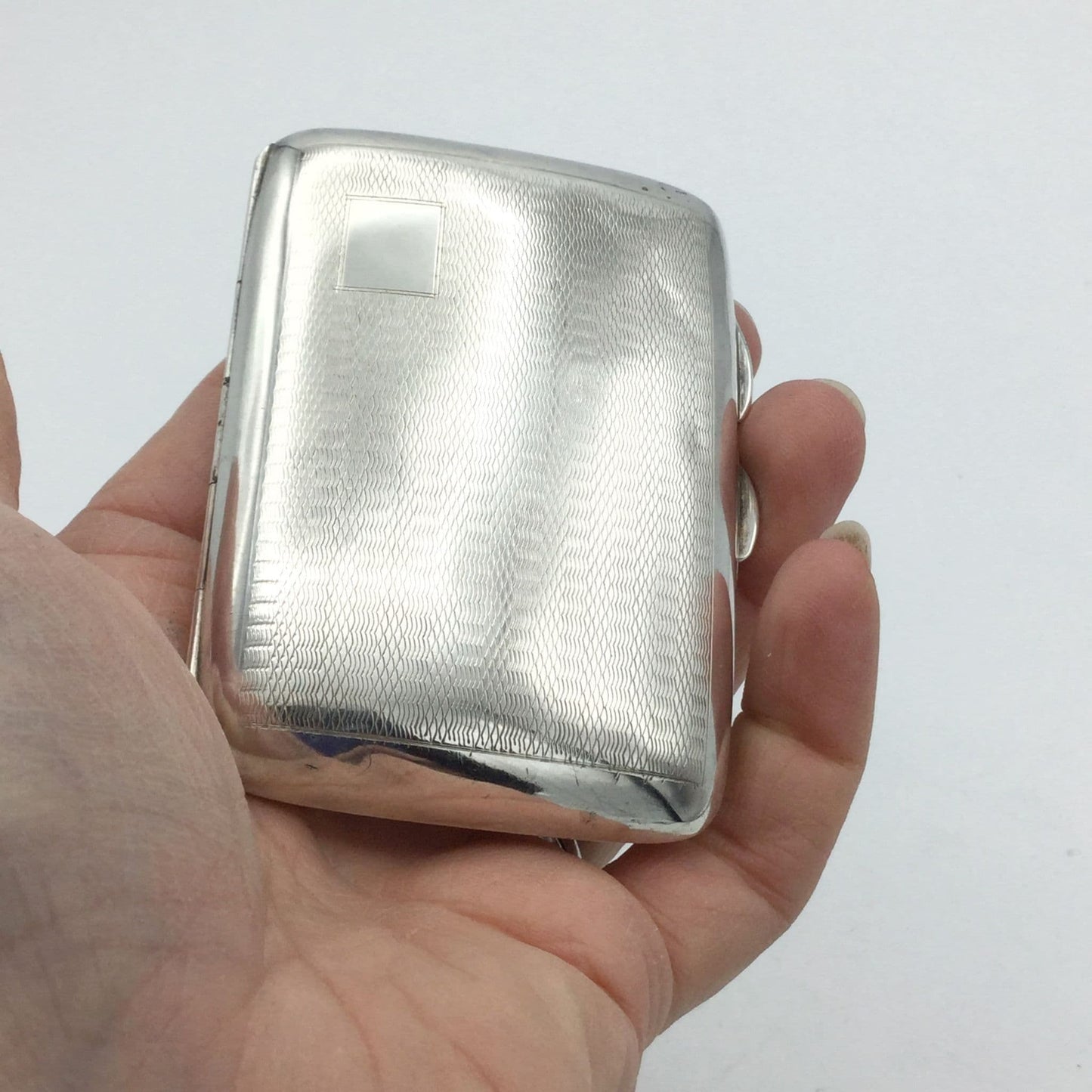 Small vintage silver cigarette case held in a hand