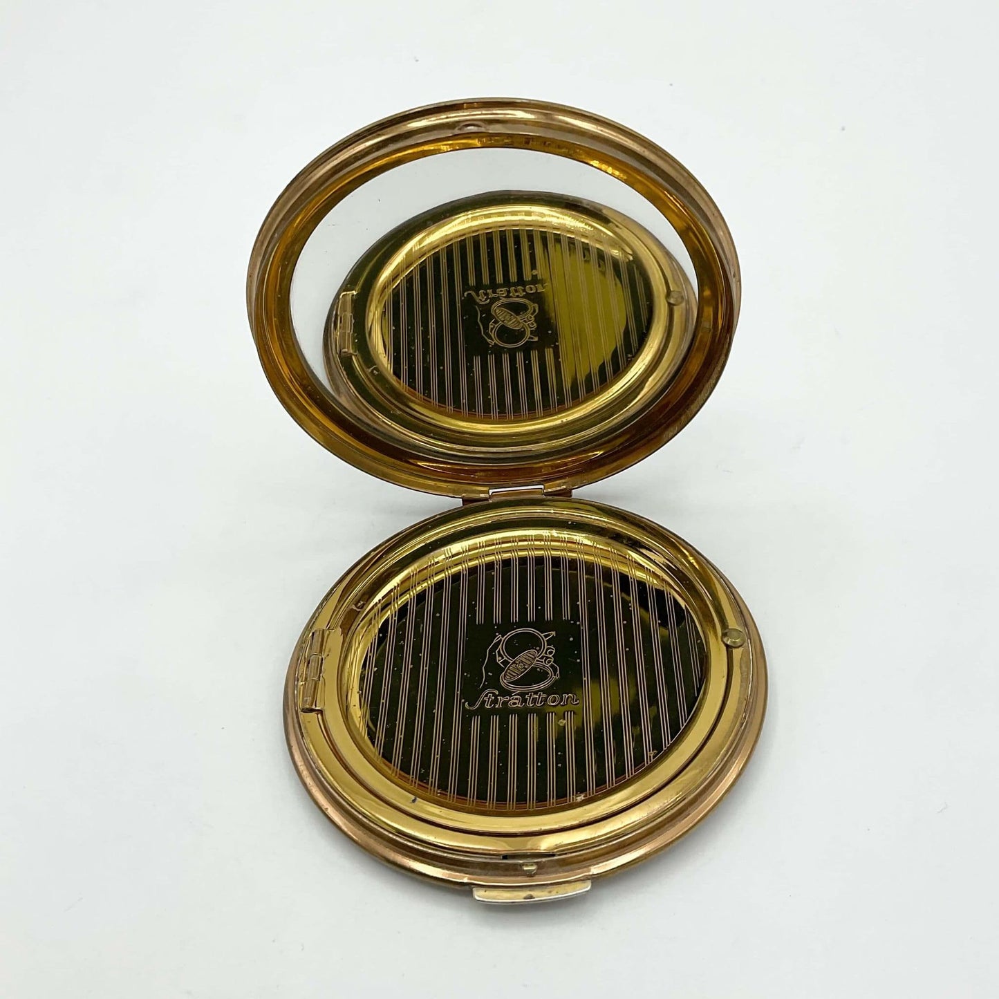 open powder compact showing a clear mirror and Stratton inner lid