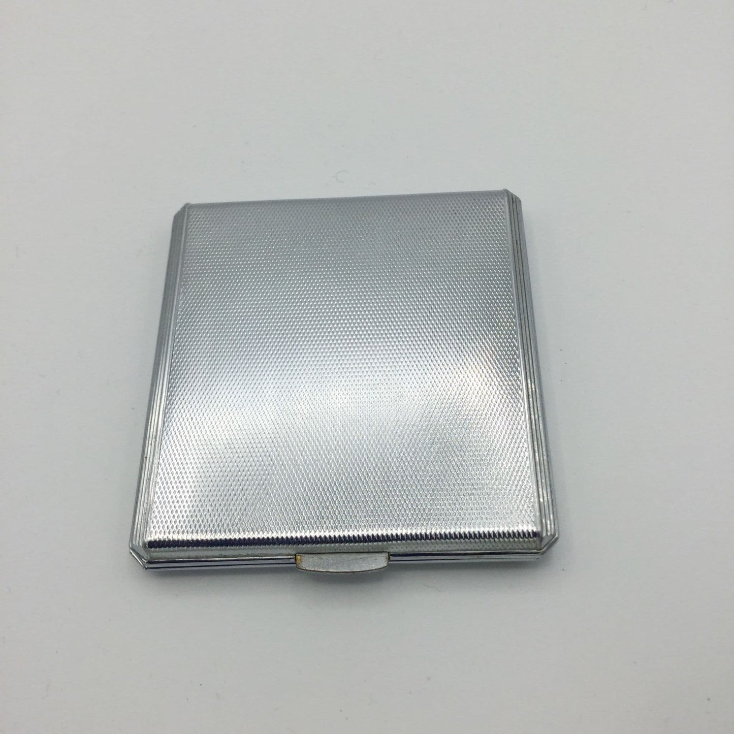 Base of silver art deco powder compact on a white background