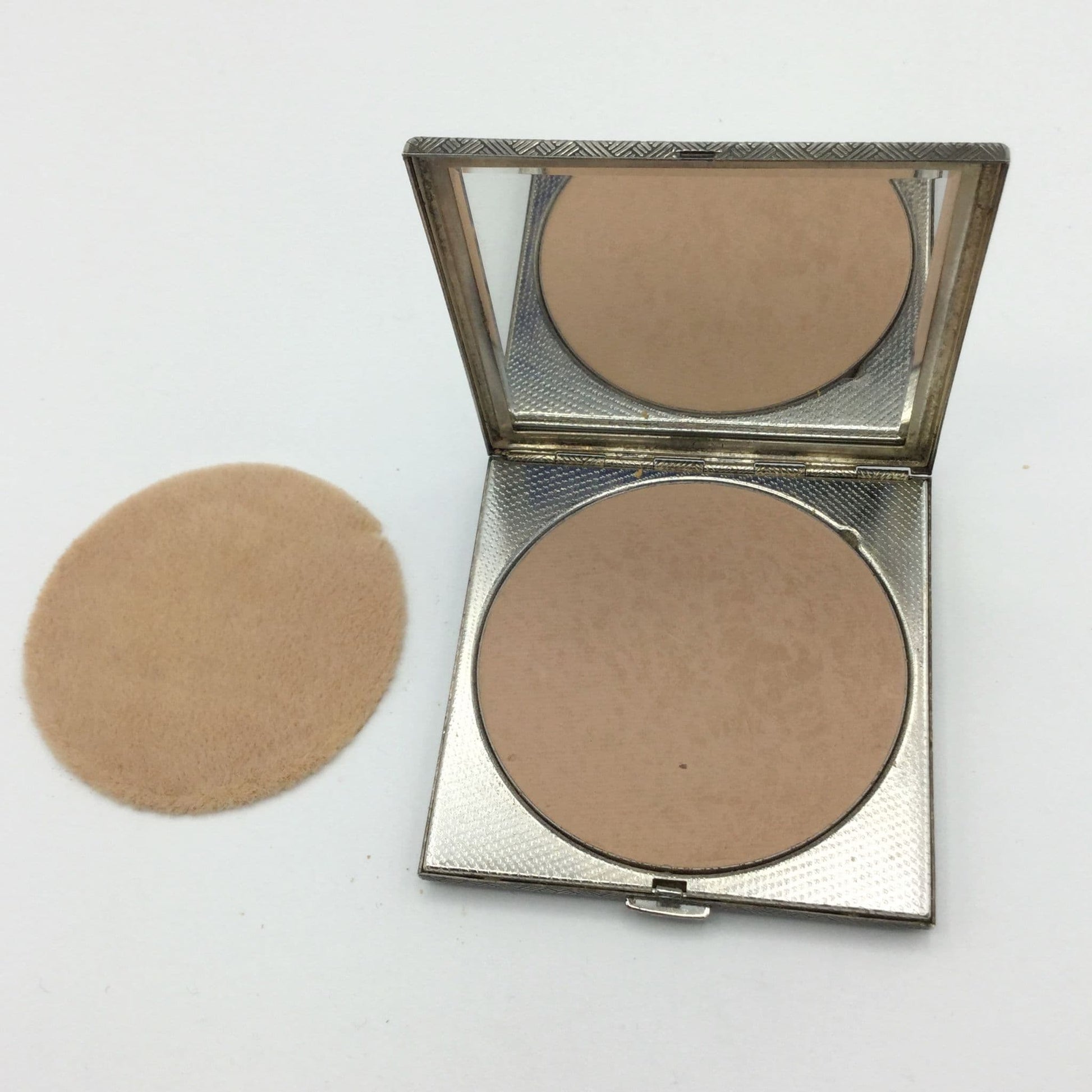open mirror compact showing powder, applicator sponge and mirror