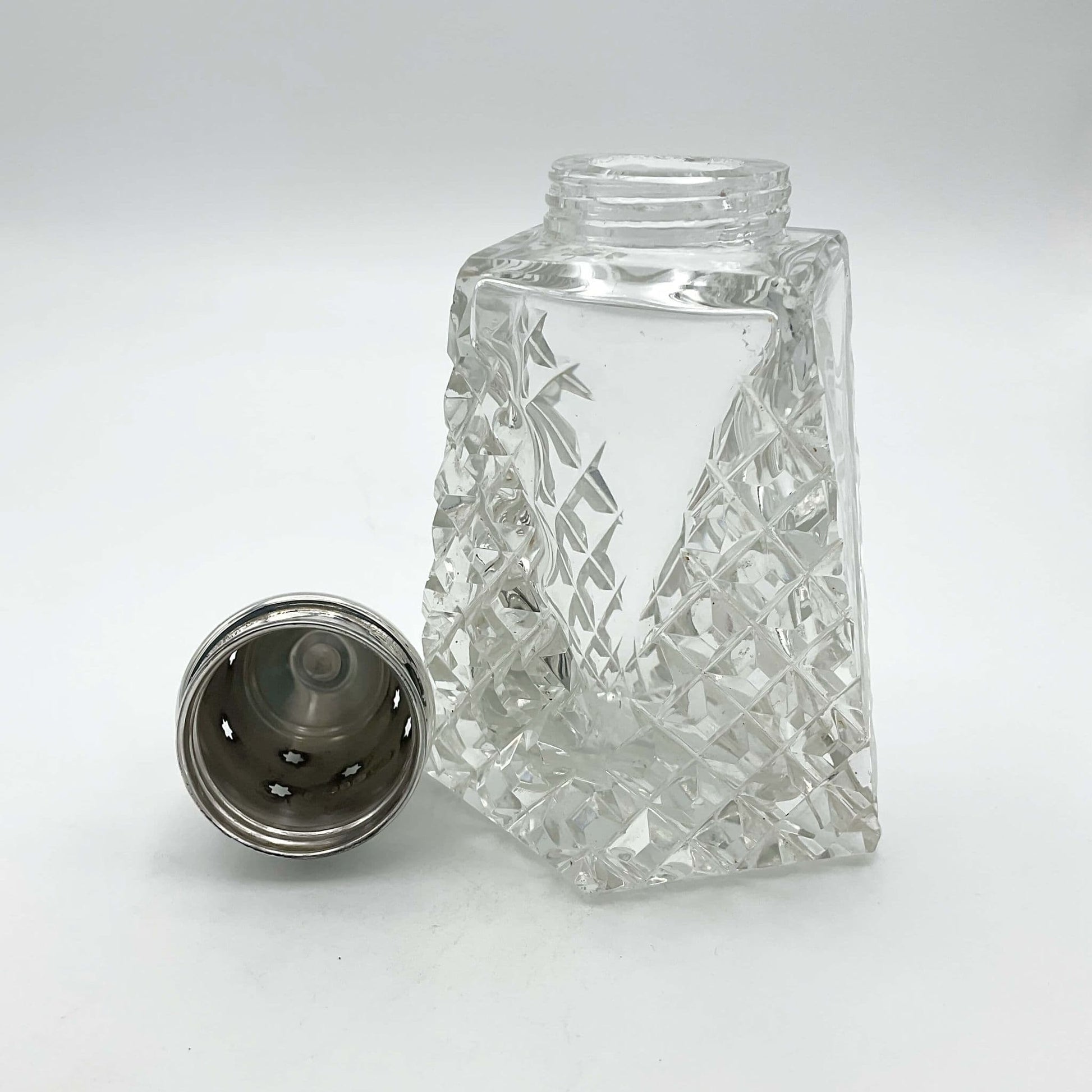 Crystal glass sugar sifter with the silver lid off sitting next to it. of sugar sh