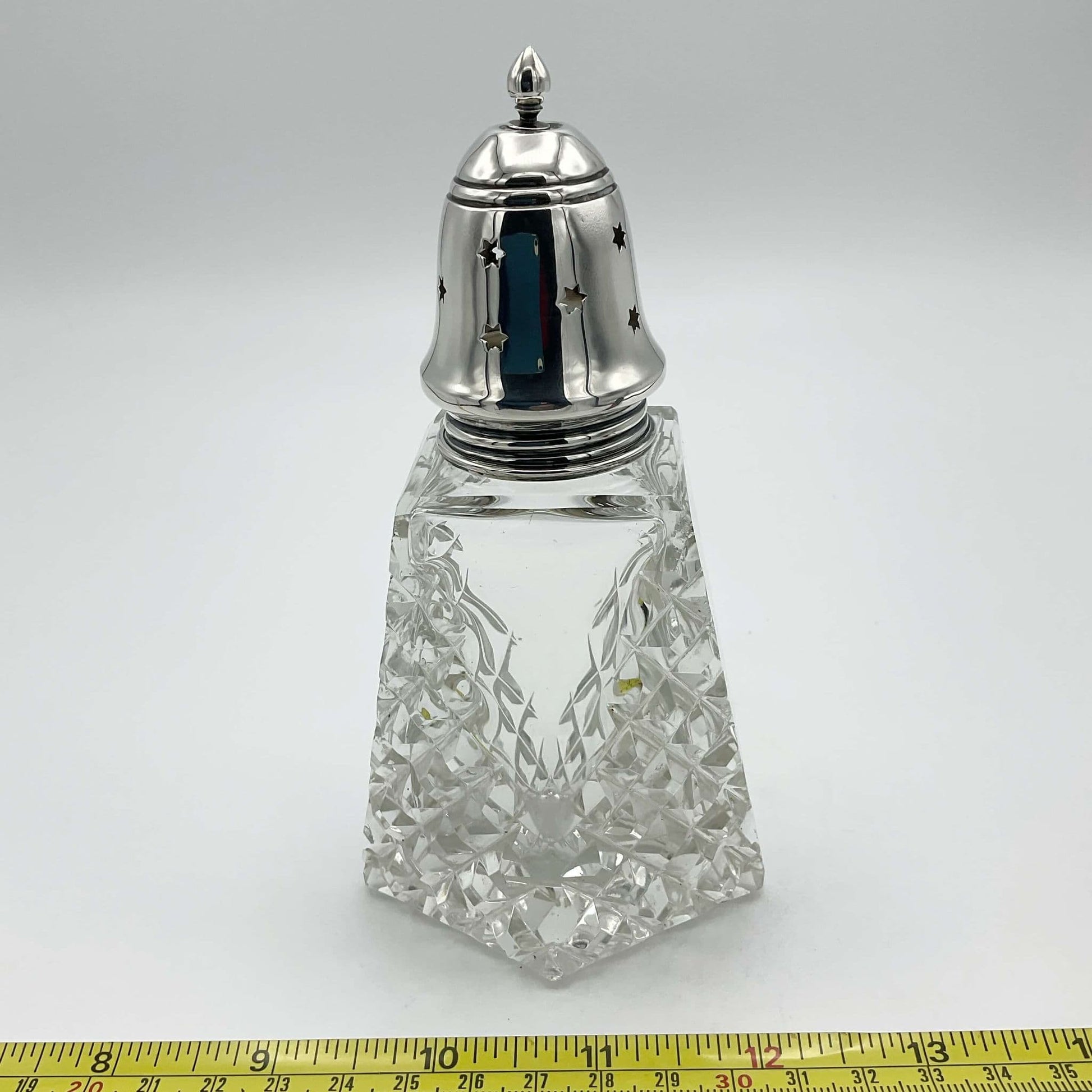Silver topped glass caster next to a tape measure showing it's width as 7cm