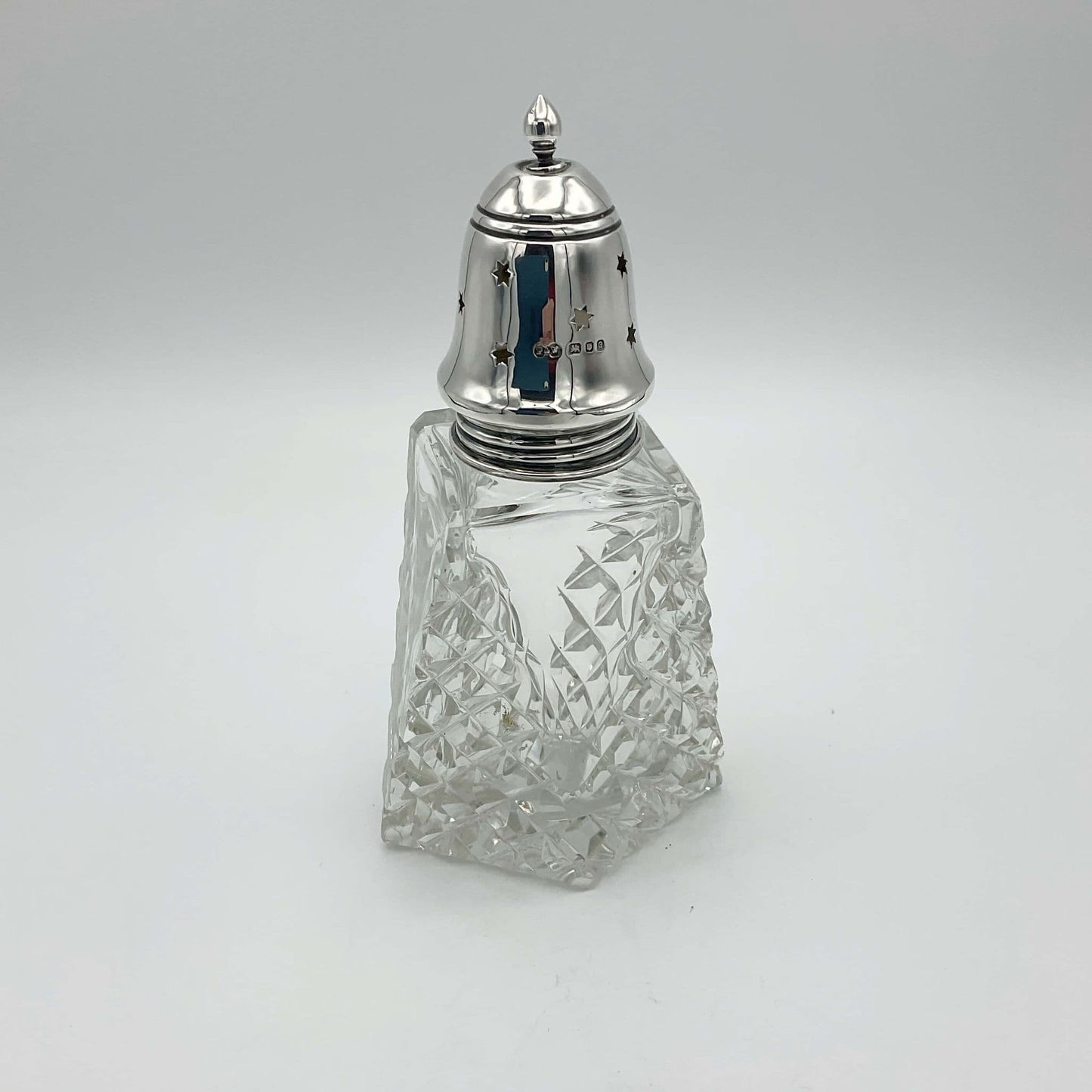 Silver topped sugar shaker with hallmarks and cut crystal glass base