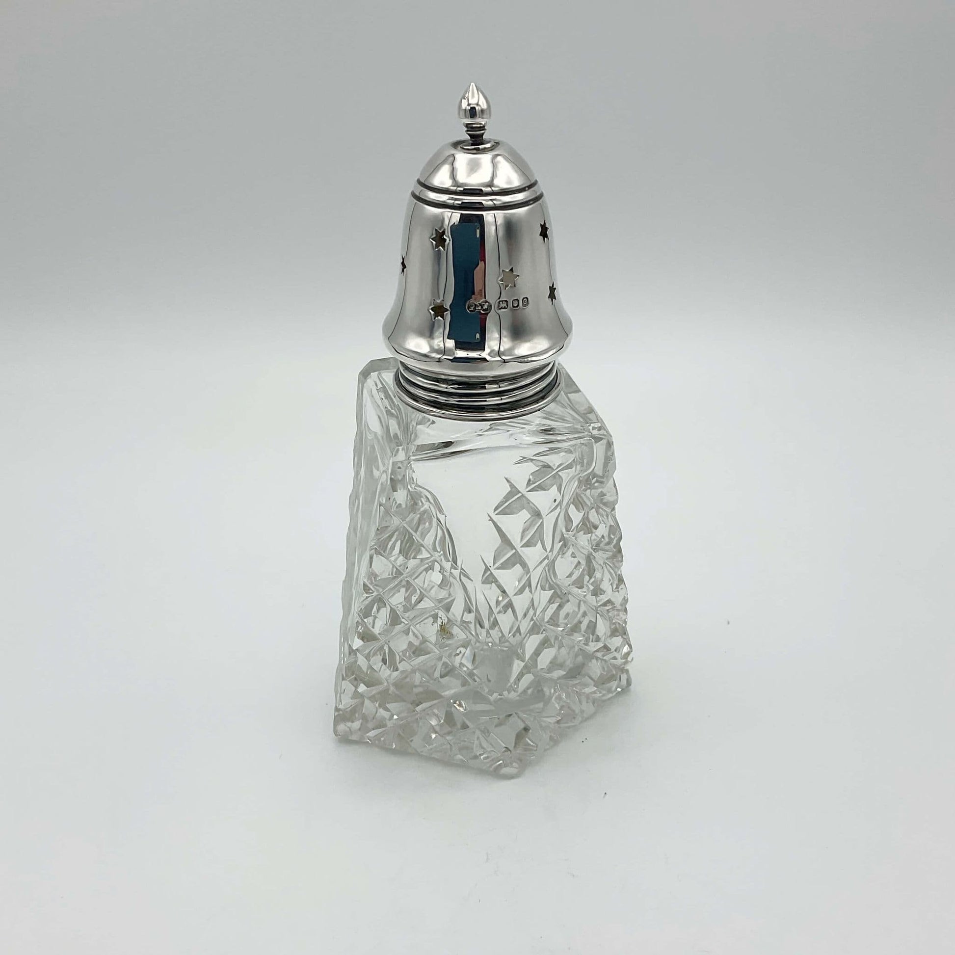 Silver topped sugar shaker with hallmarks and cut crystal glass base