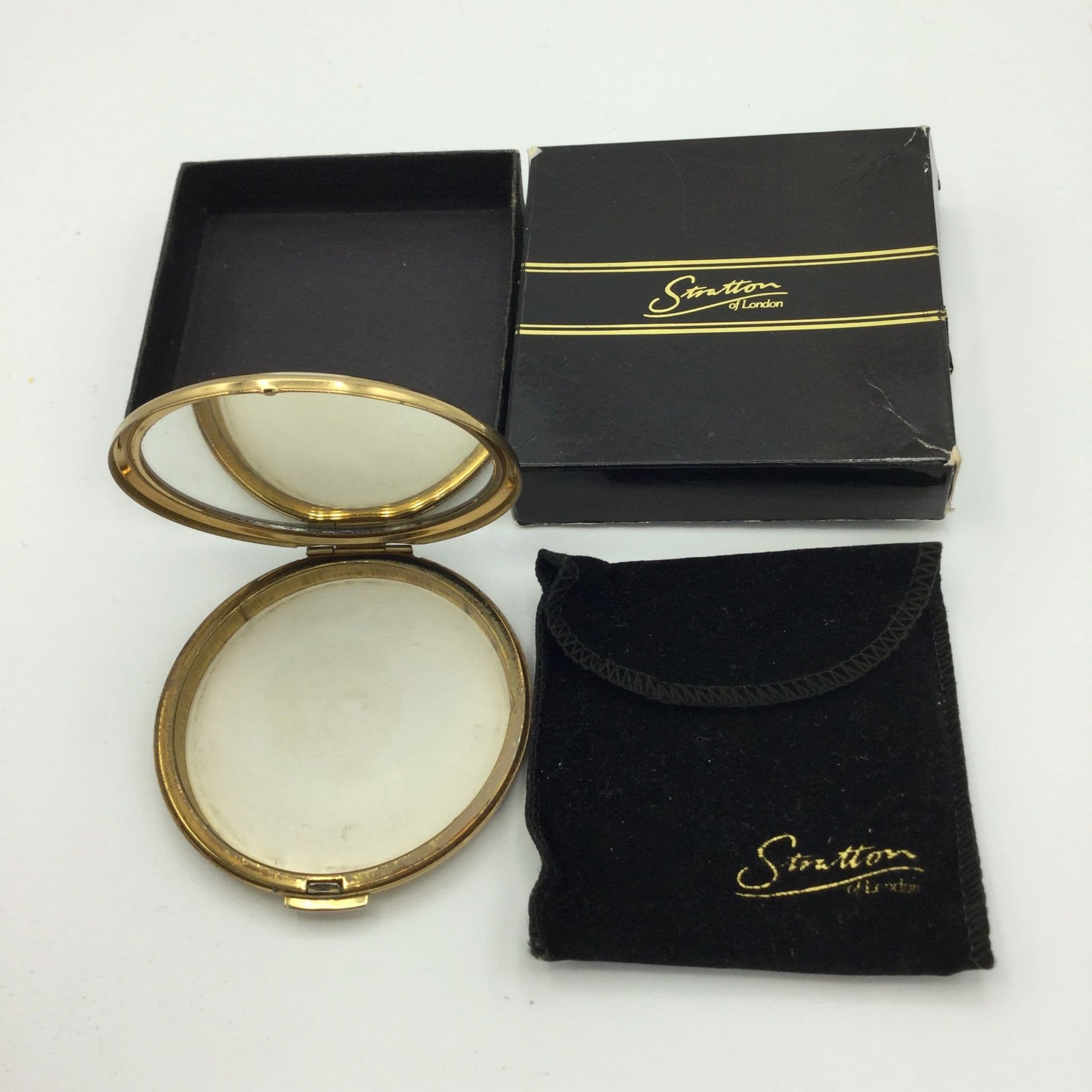 Stratton compact open with a clear mirror next to a Stratton gift box and pouch