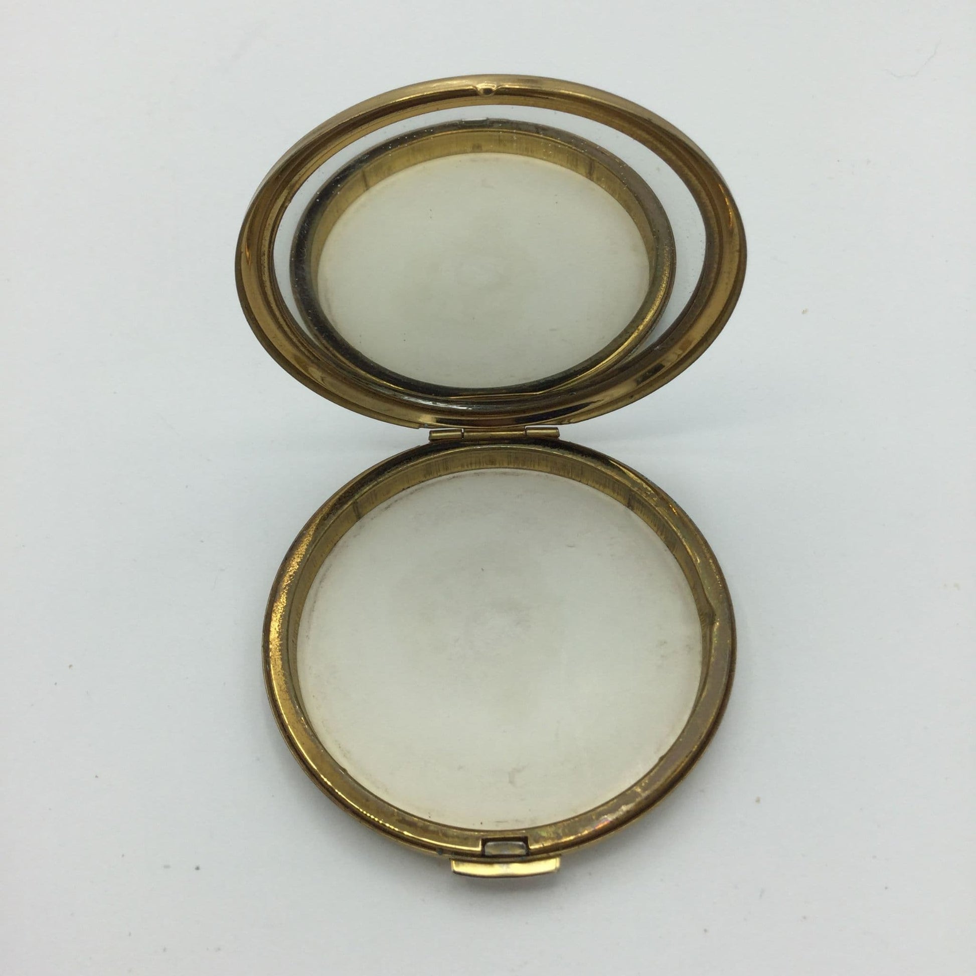 Gold edged compact with a clear mirror open on a white background