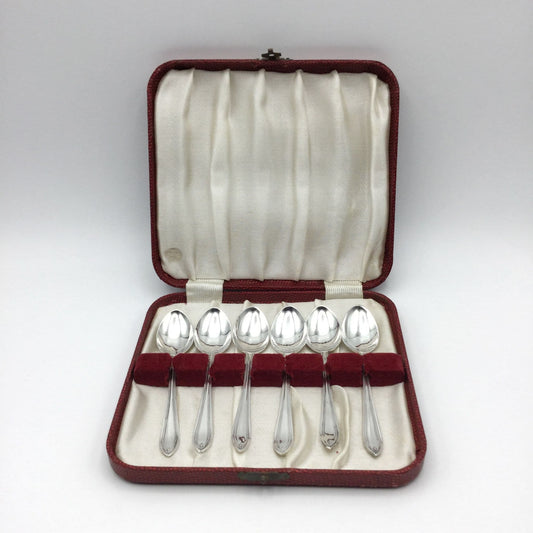Six matching 1930s silver coffee spoons sitting in a red presentation box with a cream lining.