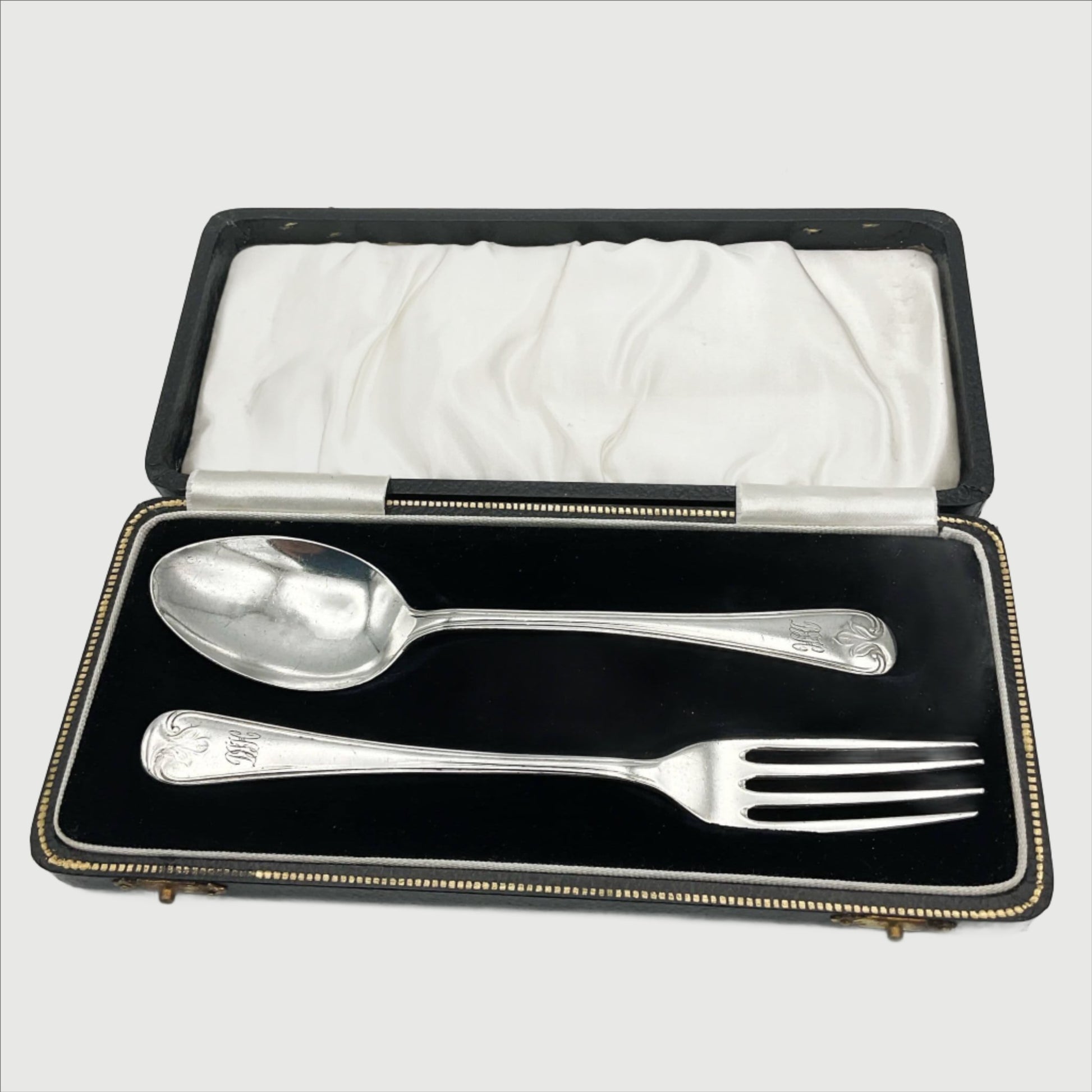 A matching silver spoon and fork sitting in a black presentation box.