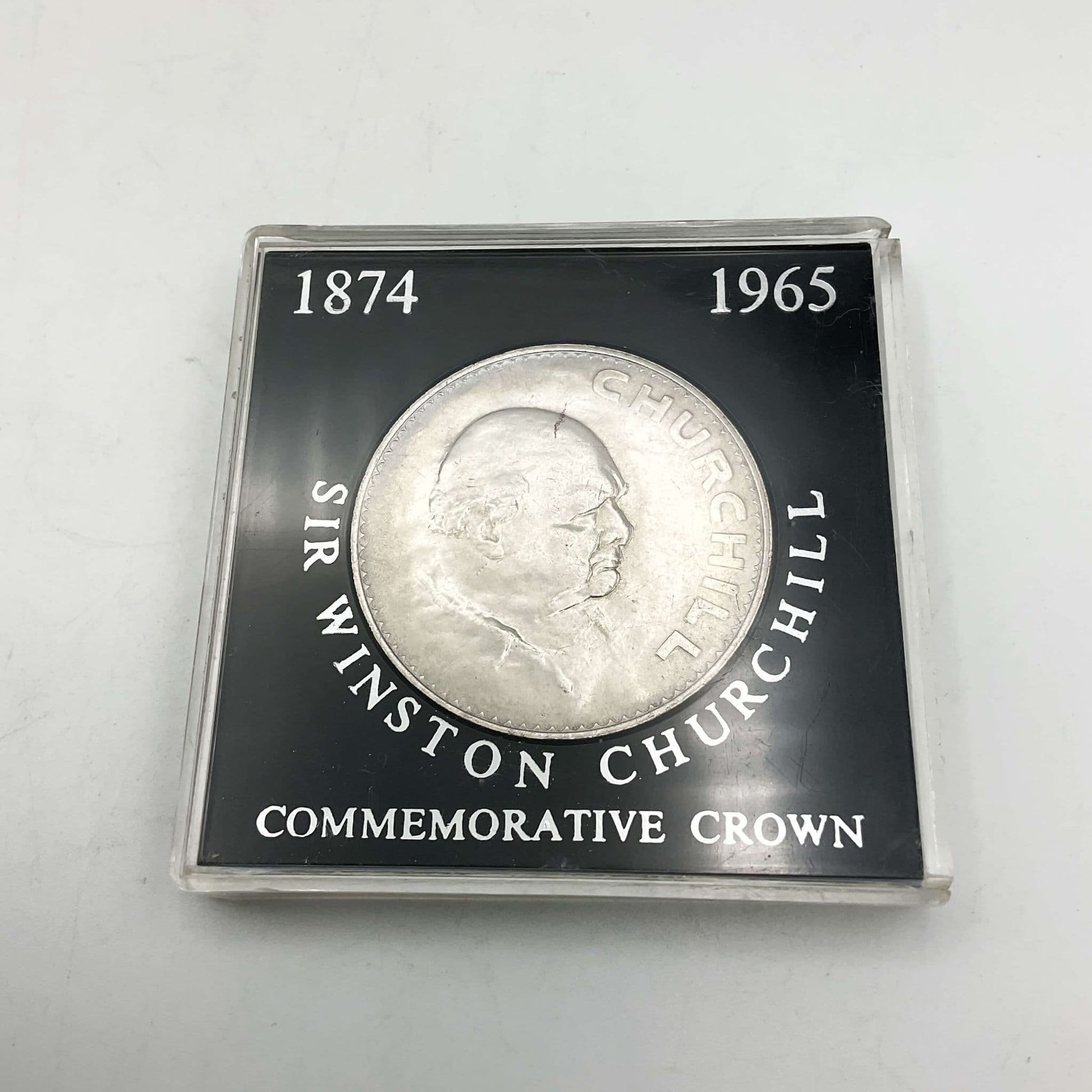 Silver coloured Winston Churchill coin with his head on a coin in a black framed case