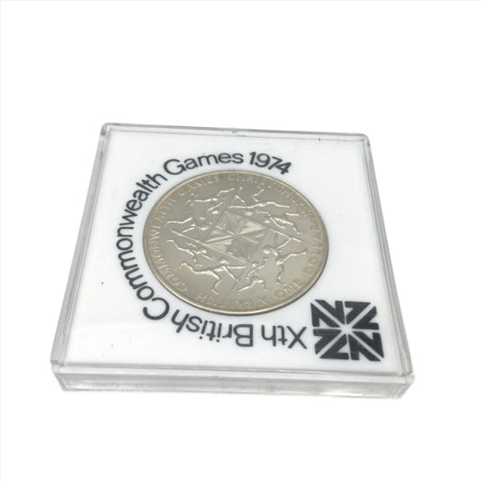 One dollar coin in a white case with 10th British Commonwealth Games 1974 around it.