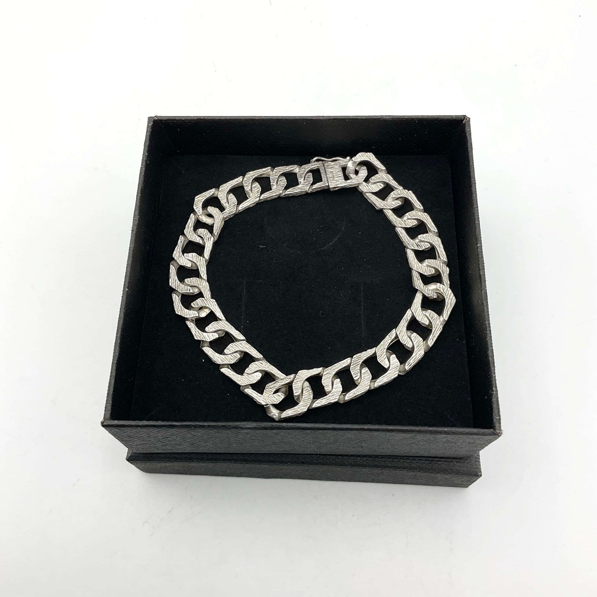 silver chain bracelet lying flat on a black presentation box
