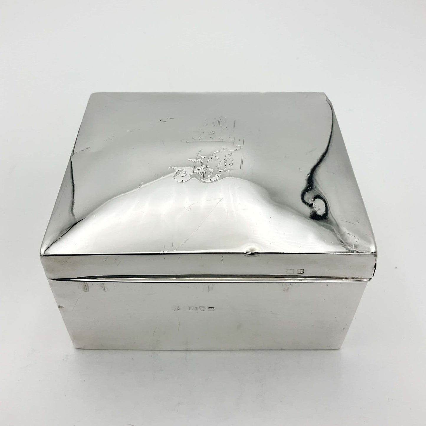 Square silver cigarette box with a engraved lid on a white background
