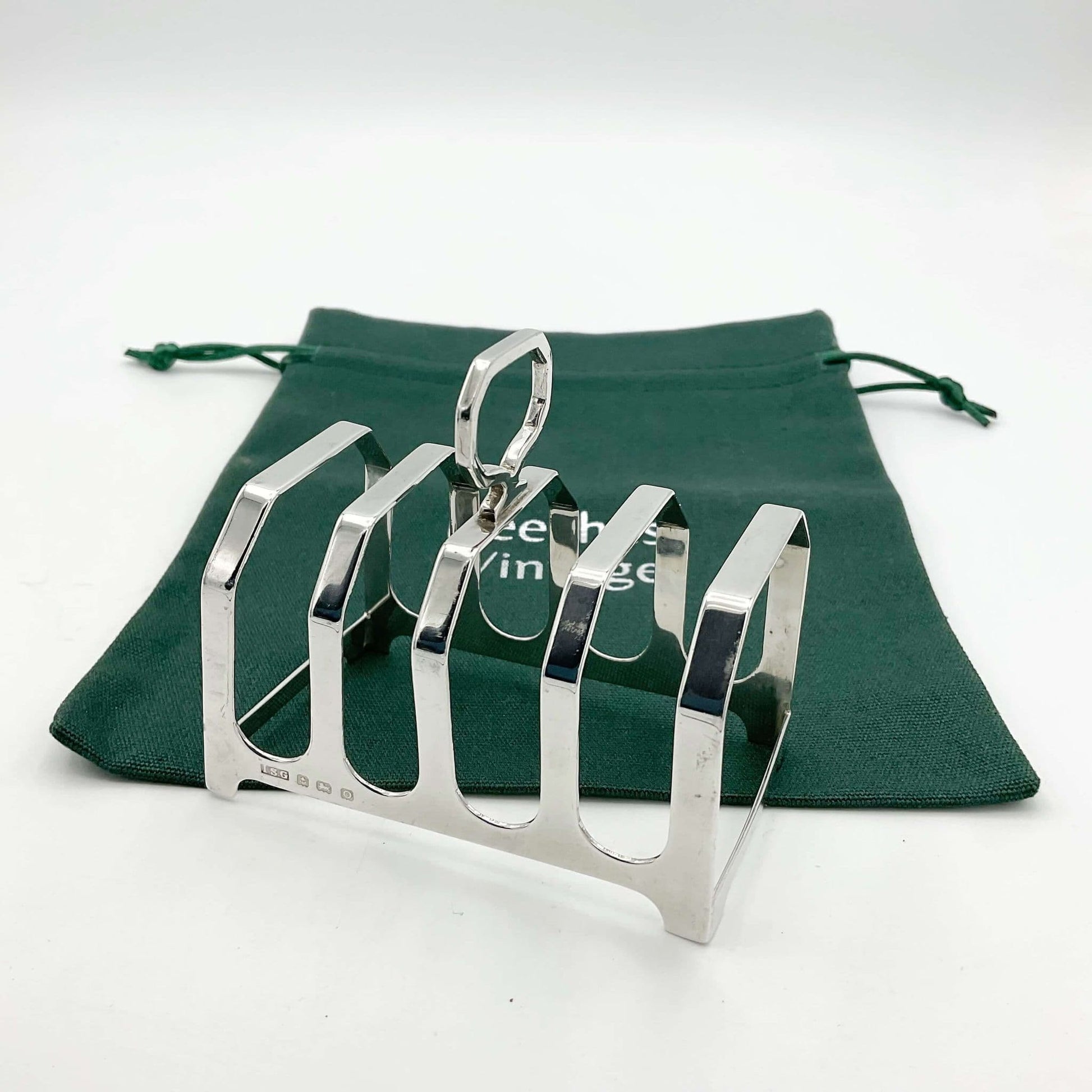 Pretty antique art deco style silver toast rack on a green cotton bag