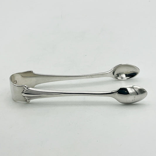 Silver sugar tongs showing an art deco design to the art on a white background