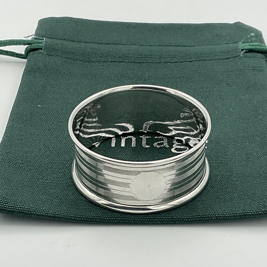 Silver napkin ring with a circular cartouche on a green bag