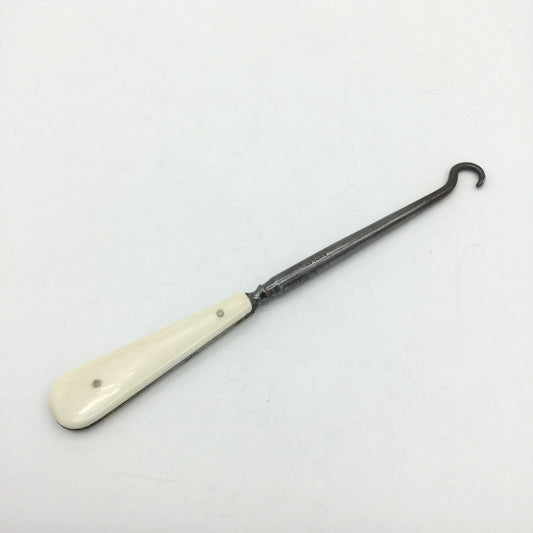 Antique bone handled button hook on a white background