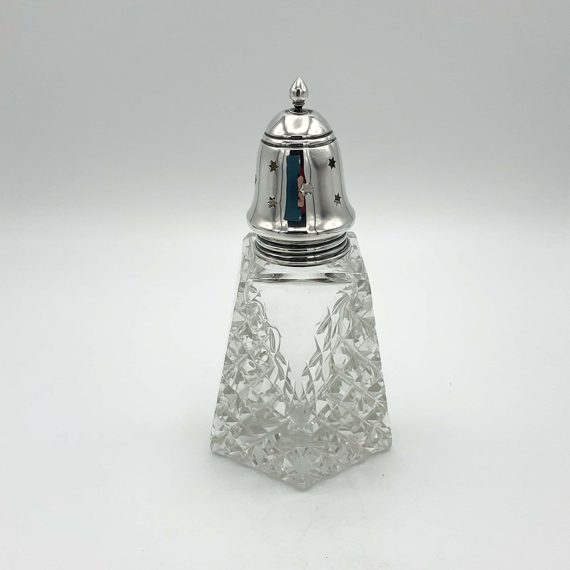 Crystal glass and silver topped sugar shaker on a white background